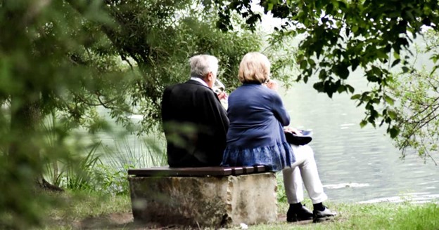 Elderly couple sitting by a pond.