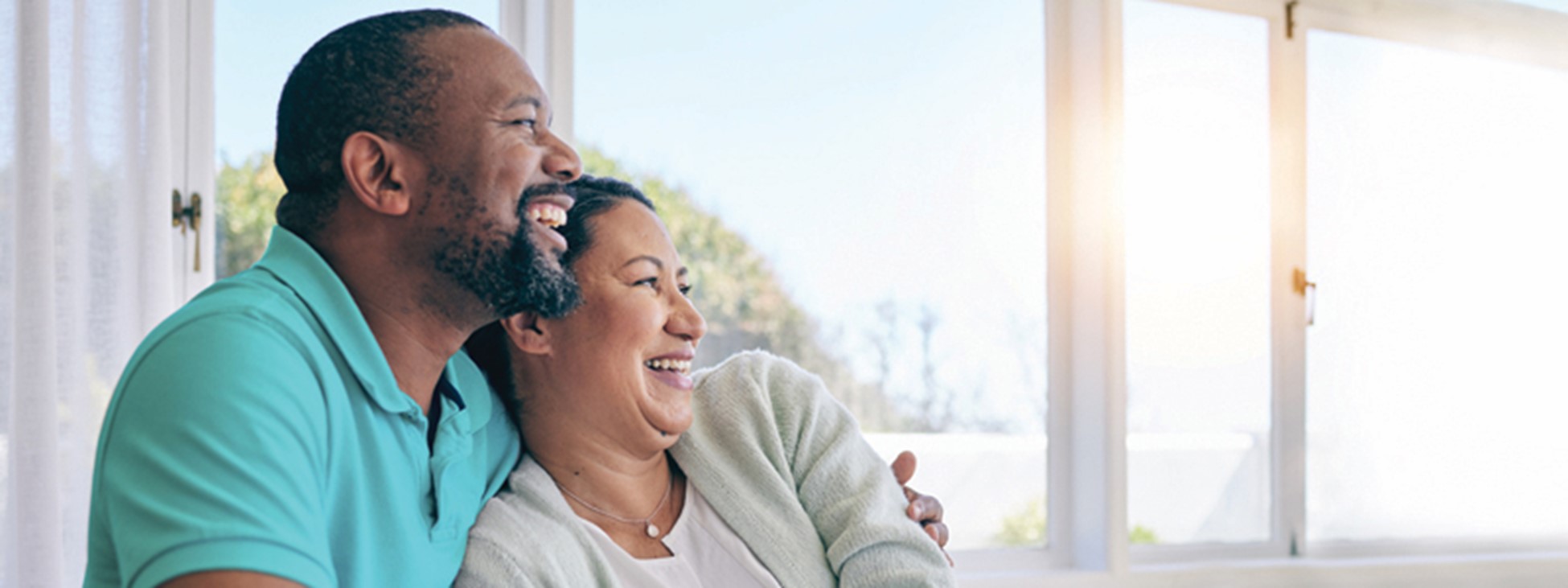 Man and woman cuddling in front of a window