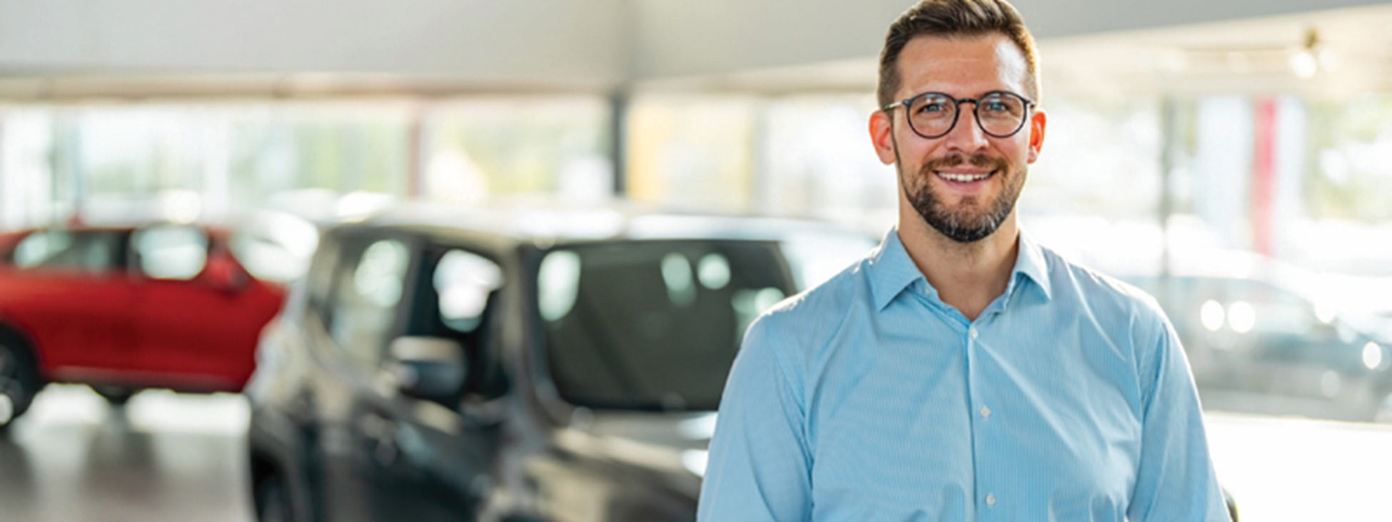Smiling man standing in front of a car