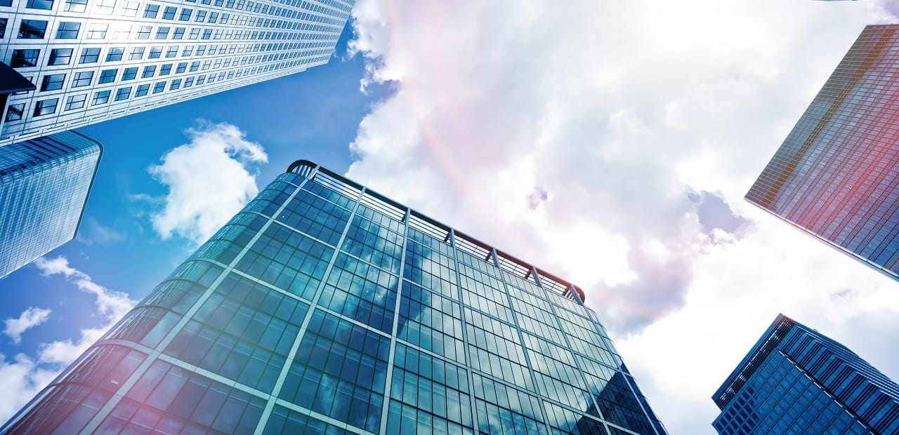 Low angle view of financial district buildings with sunny skies in background